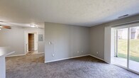 Located at 424 Spring Lake Blvd in Granger, Indiana, this single-floor, one-bedroom, one-bathroom unit offers a practical and comfortable layout. The combined kitchen and living area forms the heart of the space, with the kitchen featuring white cabinetry with wood-tone trim, light countertops, a double-basin sink, electric range, dishwasher, and refrigerator, all set over durable wood-look vinyl flooring. The living area is carpeted and bright, highlighted by a sliding glass door that opens to a view of a well-maintained green lawn, filling the space with natural light. The bedroom is a comfortable size, finished with plush carpet, neutral gray walls, a window with outdoor views, and a closet with a sliding door and built-in hanging rod. Four closets throughout the unit provide generous storage. The full bathroom includes a single-sink vanity with a large mirror, stylish vanity lighting, a soaking tub with tiled surround, and wood-look flooring. A dedicated laundry area and utility room add everyday convenience. Textured ceilings are consistent throughout, contributing to the unit's cohesive and functional design.