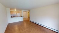 This single-floor residence offers a clean, functional layout designed for comfortable everyday living. Warm hardwood-style flooring flows consistently throughout the main living areas and bedrooms, creating a cohesive and inviting atmosphere. The open-concept living and dining area is bright and generously proportioned, featuring large windows that draw in natural light and a sliding glass door that leads to a private balcony, providing pleasant outdoor views. Baseboard heating and a wall-mounted air conditioning unit ensure year-round comfort. A ceiling fan in the hallway adds to the efficient climate control of the space. The kitchen is thoughtfully designed with light wood cabinetry, granite-style countertops, a double-basin stainless steel sink, a gas range, and a full-size refrigerator, all arranged for practical use. The bedrooms are well-sized with clean white walls, hardwood-style flooring, and dedicated closet space, including a walk-in closet in the primary bedroom. The full bathroom features a shower-tub combination, a vanity with a mirror, and lighted fixtures. Overall, the space presents a clean, neutral palette throughout, offering a solid foundation for personalization.