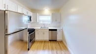 This two-floor residence offers a thoughtfully designed layout with a clean, neutral aesthetic throughout. The main living area features warm hardwood flooring and is bathed in natural light, with sliding glass doors that open to an outdoor area, creating a seamless indoor-outdoor connection. Track lighting adds a modern touch to the open living space.

The kitchen is efficiently designed with white cabinetry, light countertops, a subway tile backsplash, and a full suite of stainless steel appliances including a gas range, dishwasher, and microwave. A window above the sink brings in additional natural light, keeping the space bright and functional.

The bedrooms are carpeted for comfort and feature large windows dressed with blinds that allow for controlled natural light. One bedroom includes a mirrored sliding-door closet, offering practical storage. Additional rooms provide versatile living space, each finished with the same soft neutral palette and plush carpeting.

The bathroom is finished with classic white subway tile wainscoting, a vanity with a mirror cabinet, and clean, simple fixtures. Throughout the home, the consistent use of light tones, natural materials, and ample windows creates a bright, welcoming atmosphere well-suited for comfortable everyday living.