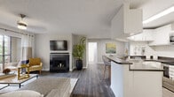 This single-floor residence offers a thoughtfully designed open-concept layout that connects the living, dining, and kitchen areas seamlessly. The living room serves as a central gathering space, anchored by a dark tile-surround fireplace and complemented by wood-look flooring that runs throughout the main areas. A pass-through bar-top kitchen features white cabinetry, stainless steel appliances including a refrigerator, range, and built-in microwave, along with a dark countertop that extends to a breakfast bar with seating. A dedicated dining nook adjacent to the kitchen provides an intimate space for meals, accented by a wall-mounted mirror that reflects natural light from nearby windows. The bedroom is generously proportioned with plush carpeting, a ceiling fan, and a large window that invites natural light and outdoor views. A second bedroom offers similar comfort and soft carpeting. The bathroom is clean and functional, featuring wood-look flooring, a vanity with dark countertop, and a large mirror. The entry foyer features paneled white doors with a modern keypad lock. Throughout the space, neutral gray tones, textured ceilings, and consistent flooring choices create a cohesive and contemporary ambiance.