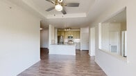 Located in Irving, TX, this well-appointed 2-bedroom, 2-bathroom single-floor residence offers a thoughtfully designed layout with a seamless blend of comfort and functionality. The open-concept living and kitchen area serves as the heart of the home, featuring rich hardwood-style flooring, a distinctive tray ceiling with crown molding, and a ceiling fan. The kitchen is equipped with stainless steel appliances, including a refrigerator, microwave, and range, complemented by a center island with granite-style countertops and sage-toned cabinetry with track lighting above. The living area flows naturally toward French doors that open to a private balcony, allowing abundant natural light throughout. The spacious primary bedroom features vaulted ceilings, multiple windows with outdoor views, a ceiling fan, and access to a generously sized walk-in closet. The second bedroom is equally bright, with a large window and its own ceiling fan. Both bathrooms are finished with granite-topped vanities and hardwood-style flooring; one features a tiled tub-shower combination. Additional highlights include seven closets providing ample storage, a dedicated laundry area, a utility room, and a hallway connecting all spaces efficiently.