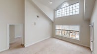 Located at Humphrey Street in Englewood, NJ, this two-floor residence offers a thoughtfully designed layout with a bright, open feel throughout. The main living area immediately impresses with soaring vaulted ceilings and a dramatic wall of windows, including an arched transom window above, flooding the space with natural light and offering views of the surrounding community. A classic wood-railed staircase with white balusters connects the two floors, adding a traditional architectural touch.

The kitchen features rich, dark wood cabinetry, granite-style countertops, stainless steel appliances including a gas range and built-in microwave, and a stainless steel sink — combining both style and functionality. The bathrooms are finished with granite countertops, undermount sinks, and white tile flooring, with the primary bath offering a dual-sink vanity and a separate shower enclosure.

The upper level hosts generously sized, carpet-floored bedrooms, each with large windows fitted with blinds that provide views of the neighborhood. A carpeted hallway with a classic railing overlook connects the upper rooms. The neutral, warm color palette used throughout creates a clean, welcoming ambiance well-suited for comfortable everyday living.