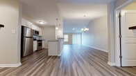 Located at 299 Leydecker Rd in Buffalo, NY, this single-floor residence offers a thoughtfully designed open-concept layout that seamlessly connects the kitchen, dining, and living areas. The kitchen is appointed with crisp white shaker cabinetry, granite countertops, a central island with pendant lighting, and a full suite of stainless steel appliances including a gas range, microwave, and refrigerator. Wide-plank wood-style flooring flows throughout the main living areas, complemented by a chandelier and ceiling fan that add both style and comfort. Large windows with horizontal blinds invite ample natural light into the living space, enhancing the bright and airy atmosphere. The bedrooms feature soft wall-to-wall carpeting and generous windows, creating a warm and restful environment. At least one bedroom includes access to a spacious walk-in closet with built-in shelving. The bathrooms are finished with white cabinetry, granite-topped vanities, brushed nickel fixtures, and wood-style flooring, delivering a clean and modern aesthetic. The overall design is neutral and contemporary, offering a move-in-ready environment with consistent, quality finishes throughout.