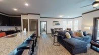 This single-floor residence at Victory Knoll offers a thoughtfully designed open-concept layout that seamlessly connects the kitchen, dining, and living areas. The kitchen serves as a functional centerpiece, featuring dark cabinetry extending to the ceiling, stainless steel appliances, a tile backsplash, and a generously sized granite island with bar seating — ideal for both meal preparation and casual dining. Crown molding and light wood-look flooring flow throughout the main living areas, lending a cohesive and polished aesthetic.

The dining area accommodates a full-sized table and benefits from a bay of windows that invite natural light. Adjacent to it, the living room provides ample space for relaxed seating and includes French doors leading to an outdoor balcony, a ceiling fan, and views of the surrounding greenery.

Multiple bedrooms are fitted with plush carpeting, ceiling fans, and large windows that frame outdoor views. Each room offers a calm, restful atmosphere. The bathroom features a dark-cabineted vanity with granite countertops and wood-look vinyl flooring. Dark-stained interior doors and consistent crown molding throughout tie the overall design together with a clean, modern sensibility.