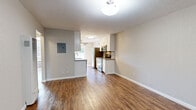 Located in Lafayette, CA, this thoughtfully updated single-floor residence combines modern finishes with a clean, functional layout. Rich wood-look flooring runs consistently throughout the space, lending warmth and visual continuity to every room.

The open living area offers a generous, versatile footprint with neutral gray walls, ample wall space, and a front entry door framed by a window that allows natural light to filter in. A wall-mounted HVAC unit and a large ventilation panel ensure year-round comfort.

The galley-style kitchen is a standout feature, outfitted with crisp white shaker cabinetry, stainless steel appliances including a refrigerator, range, microwave, and dishwasher, and a mosaic tile backsplash that adds a refined touch. Light countertops complement the cabinetry, while a sliding glass door at the end of the kitchen opens to an outdoor area, inviting natural light deep into the space. A ceiling fan overhead enhances airflow.

The bedroom offers a calm, neutral palette with a window providing natural light and a wall-unit HVAC for individual climate control.

The bathroom is finished with large-format gray tile surrounding the tub and shower, accented by a decorative mosaic border. Wood-look flooring, a vanity with a stone-look countertop, and brushed nickel fixtures complete the space with a cohesive, contemporary feel.