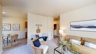 Located in Salem, Oregon, this two-bedroom, one-bathroom single-floor residence offers a thoughtfully designed layout with a warm, neutral palette throughout. The living room is a welcoming space with plush carpet, a large window inviting natural light, and a seamless flow into the entryway, which features built-in coat hooks and bench seating. Adjacent to the living area, the dedicated dining space accommodates a small table and chairs beneath another window overlooking the landscaped exterior. The galley-style kitchen is efficiently arranged with wood-toned cabinetry, white appliances, ample counter space, and a stainless steel sink — with a convenient pass-through view to the in-unit laundry area housing a full-size washer and dryer. The primary bedroom is a comfortable retreat with multiple windows on two walls, filling the room with natural light. The second bedroom offers carpeted floors and generous wall space. Three closets throughout the unit provide ample storage. The full bathroom features a wood-toned vanity, large mirror, and updated light fixtures. Wood-look flooring ties together the kitchen, dining, and bathroom areas, complementing the carpeted living and sleeping spaces for a cohesive, functional home.