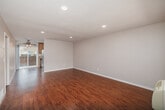 Located at 10233 Mission Gorge Road in Santee, California, this two-bedroom, one-bathroom single-story home offers a functional and comfortable layout. The living room features warm wood-look flooring, recessed lighting, and a wall-unit air conditioner, creating a bright and welcoming atmosphere with natural light filtering through vertical blinds. It flows seamlessly into the combined dining and kitchen area, which is outfitted with classic oak cabinetry, granite-look countertops, a double basin sink, and stainless steel appliances including a refrigerator, range, and dishwasher — all set atop matching wood-look flooring. A hallway connects the main living spaces to the two bedrooms, each finished with plush carpeting and ceiling fans with integrated lighting. The spacious primary bedroom features a mirrored sliding-door closet and a window for natural light. The second bedroom also includes carpeting, a window with vertical blinds, and access to closet space. The full bathroom includes a shower-tub combination, a vanity with storage, wood-look flooring, and a high window for ventilation. Four closets throughout provide ample storage. A private patio rounds out this well-appointed home.