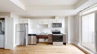 This well-appointed bachelor unit at 62 Armstrong Crt in Halifax, Nova Scotia, offers a thoughtfully designed single-floor layout that maximizes every square foot. Light-toned hardwood flooring flows consistently throughout the open-concept living space, creating a cohesive and airy feel. Large windows allow abundant natural light to fill the living area, which also features a wall-mounted mini-split system and baseboard heating for year-round comfort, along with a sliding door that opens to an outdoor area with neighbourhood views.

The modern kitchen is efficiently designed with white upper cabinetry, dark wood-toned lower cabinets, and light countertops. A full suite of stainless steel appliances — including a refrigerator, electric range, over-the-range microwave, and dishwasher — provides all the essentials for daily living. A dedicated closet off the main corridor houses a stacked washer and dryer, offering the convenience of in-unit laundry.

The bathroom is finished with large-format tile flooring, a floating dark wood vanity with an integrated sink, a full mirror, and a tub-shower combination with glass enclosure and grab bars. A built-in closet with shelving provides additional storage. The unit's clean, neutral palette and modern finishes make it a functional and stylish living space.