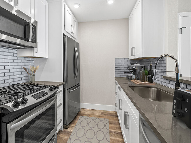 Blue tiled kitchen with stainless steel fridge, oven, and fixtures. - Catalina Apartments