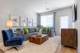 This single-floor residence offers a thoughtfully designed open-concept layout, connecting the kitchen, dining, and living areas into one cohesive and airy space. Light wood-style flooring flows throughout the main living areas, complementing the clean white walls and creating a bright, contemporary atmosphere.

The kitchen is outfitted with dark espresso cabinetry, granite countertops, stainless steel appliances including a refrigerator, gas range, microwave, and dishwasher, and a central island with pendant lighting overhead. A double-door entry closet near the foyer provides additional storage convenience.

The open living area is generously proportioned, featuring multiple windows with blinds that invite abundant natural light. A glass-paned exterior door further brightens the space and provides outdoor access.

The bedroom offers plush carpeting, a window with natural light, and ample room for furnishings. The en-suite bathroom is well-appointed with a dual-sink granite vanity, dark cabinetry, a walk-in glass-enclosed shower, and light wood-style flooring, delivering a clean, spa-like aesthetic throughout.