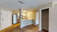 This single-floor residence at 3920 Knickerbocker Way in Raleigh, NC offers a well-designed layout that balances functionality and comfort. The open-concept kitchen is a central highlight, featuring white shaker cabinetry, white quartz countertops, a peninsula with a sink, and a full suite of stainless steel appliances including a refrigerator, range, and over-the-range microwave. Wood-style flooring runs throughout the main living areas, lending warmth and continuity to the space.

The living area is generously sized, bathed in natural light through large windows and a sliding glass door that opens to a private patio, offering pleasant outdoor views of lush greenery. A chair-rail accent along the wall adds a subtle architectural detail to this bright, open room.

The bedrooms are finished with plush carpeting, providing a comfortable retreat, and feature closet storage. One bedroom connects conveniently to an adjacent space with additional shelving and storage.

The bathroom is clean and well-appointed, with a tiled tub-surround shower, a wide vanity with quartz countertop, gray cabinetry, and a large mirror. Textured ceilings are present throughout the unit. Additional storage in the form of a closet near the kitchen entry adds practicality to this thoughtfully laid-out space.