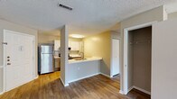 This single-floor residence at 3920 Knickerbocker Way in Raleigh, NC offers a well-designed layout that balances functionality and comfort. The open-concept kitchen is a central highlight, featuring white shaker cabinetry, white quartz countertops, a peninsula with a sink, and a full suite of stainless steel appliances including a refrigerator, range, and over-the-range microwave. Wood-style flooring runs throughout the main living areas, lending warmth and continuity to the space.

The living area is generously sized, bathed in natural light through large windows and a sliding glass door that opens to a private patio, offering pleasant outdoor views of lush greenery. A chair-rail accent along the wall adds a subtle architectural detail to this bright, open room.

The bedrooms are finished with plush carpeting, providing a comfortable retreat, and feature closet storage. One bedroom connects conveniently to an adjacent space with additional shelving and storage.

The bathroom is clean and well-appointed, with a tiled tub-surround shower, a wide vanity with quartz countertop, gray cabinetry, and a large mirror. Textured ceilings are present throughout the unit. Additional storage in the form of a closet near the kitchen entry adds practicality to this thoughtfully laid-out space.