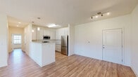 Located at 40 Cohen Walker Dr in Warner Robins, GA, this single-story, 3-bedroom, 2-bathroom home offers a thoughtfully designed open-concept layout with consistent wood-look flooring throughout. The combined living and dining area is bright and spacious, featuring ceiling fans, track lighting, and a door providing direct access to the outdoors with views of the surrounding neighborhood.

The kitchen is a standout feature, equipped with crisp white shaker-style cabinetry, granite countertops, stainless steel appliances including a range, over-the-range microwave, and refrigerator, along with a central island with pendant lighting — ideal for both cooking and casual dining.

The generously sized primary bedroom includes a ceiling fan, a window with natural light, and access to a walk-in closet outfitted with wire shelving systems. The bathrooms feature granite-topped vanities with ample cabinetry. One bathroom conveniently incorporates a stacked washer and dryer unit, streamlining laundry needs.

Two additional bedrooms mirror the home's clean, neutral aesthetic with wood-look flooring, ceiling fans, and natural light. The attached garage offers substantial storage or parking space and includes an automatic opener. Throughout, the home maintains a clean, modern palette of neutral tones, making it move-in ready.