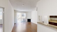 This 2-bedroom, 2-bathroom residence is laid out across a single floor, offering a practical and comfortable living arrangement. The combined kitchen and living room serves as the heart of the home, featuring warm hardwood flooring that flows throughout the main living areas. A corner fireplace anchors the living space, while a full-width sliding glass door opens to a private balcony, flooding the room with natural light and providing outdoor views. A convenient pass-through granite countertop connects the living area to the kitchen, enhancing the open feel between the two spaces. The galley-style kitchen is well-equipped with rich dark wood cabinetry, granite countertops, a gas range, and a full-size refrigerator, all complemented by light tile flooring. Both bedrooms are finished with hardwood floors and white walls, creating bright, neutral spaces. The primary bedroom offers a comfortable footprint with direct access to one of the two bathrooms. Each bathroom features a tub-shower combination — one with white tile surround and another with a dark-framed vanity mirror, warm wood cabinetry, and granite countertops. A dedicated closet provides additional storage. The textured ceilings and clean white walls give the entire residence a cohesive, move-in-ready aesthetic.