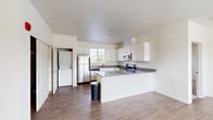 This single-floor residence offers a clean, modern aesthetic throughout, with a well-designed layout that balances open communal areas with private living spaces. The living room is a welcoming focal point, finished with wood-look luxury vinyl plank flooring and anchored by a tile-surround fireplace with a rustic wood mantel. Large windows fitted with blinds allow abundant natural light while providing views of the surrounding greenery, creating a bright and airy atmosphere.

The kitchen is designed for functionality and style, featuring white shaker cabinetry, gray laminate countertops, and a peninsula that extends the workspace and defines the boundary between kitchen and living areas. Stainless steel appliances — including a refrigerator, range, microwave, and dishwasher — are thoughtfully integrated. A dedicated in-unit laundry area with a stacked washer and dryer is conveniently accessible from the kitchen.

The bedrooms are carpeted for comfort and receive natural light through windows with outdoor views. At least one bedroom offers direct access to a bathroom, which features tile flooring and a window for ventilation. The overall palette of crisp white walls and neutral finishes gives the entire space a clean, cohesive character.