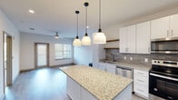 Located at 4233 Third Ave S in Birmingham, Alabama, this single-floor residence showcases a clean, contemporary design throughout. The heart of the home is an open-concept kitchen that impresses with a generously sized granite-topped island, crisp white cabinetry, a warm wood floating shelf, and a textured tile backsplash. A trio of pendant lights hangs above the island, adding both style and focused illumination. The kitchen is fully equipped with stainless steel appliances, including a refrigerator with ice maker, range, over-the-range microwave, and dishwasher. Light wood-look flooring flows seamlessly from the kitchen into the adjacent living area, which benefits from natural light through well-placed windows and is accented by a ceiling fan overhead. The bedrooms are carpeted for comfort, each featuring recessed lighting and access to natural light. One bedroom includes a direct connection to a private bathroom. The bathroom is outfitted with a soaking tub and shower combination finished with elegant large-format marble-style tile. Throughout the space, neutral tones and modern finishes create a cohesive, move-in-ready atmosphere that is both functional and inviting.