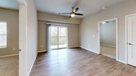 Located at 1735 E Valley Water Mill Rd in Springfield, MO, this single-floor, 2-bedroom, 2-bathroom residence offers a thoughtfully designed layout with modern finishes throughout. The open-concept kitchen and living area serves as the heart of the home, featuring crisp white shaker cabinetry, granite countertops, a central island, and a full suite of stainless steel appliances including a refrigerator, dishwasher, electric range, and microwave. Recessed lighting illuminates the kitchen, while wood-look flooring extends through the main living areas. The living room is bathed in natural light from sliding glass doors that open to a private balcony with outdoor views, complemented by a ceiling fan overhead. Both bedrooms are carpeted for comfort, with neutral tones and ample closet space featuring wire shelving systems. The bathrooms are finished with granite-topped vanities and hardwood-style flooring. Additional conveniences include a dedicated laundry area and utility room. The overall aesthetic is clean and contemporary, with a warm, neutral color palette that creates a bright and welcoming atmosphere throughout the home.