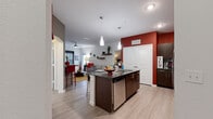 This single-floor, 2-bedroom, 2-bathroom residence in San Antonio, Texas offers a well-designed open-concept layout that seamlessly connects the kitchen, dining, and living areas. The kitchen is a standout feature, boasting dark espresso cabinetry, granite countertops, a mosaic tile backsplash, stainless steel appliances, and a central island with bar seating — all accented by bold red walls and sleek pendant lighting. Light wood-style flooring flows throughout the main living areas, complementing the bright, neutral palette. The living room is spacious and comfortable, featuring a ceiling fan, floating wall shelves, and windows that invite natural light. Both bedrooms are carpeted and well-proportioned, offering ample natural light through large windows. The primary bathroom features dark cabinetry with granite countertops, a wide vanity mirror with lighted fixtures, and light flooring for a clean, contemporary feel. The secondary bathroom includes a soaking tub with subway tile surround and dark overhead cabinetry. Arched architectural details add a distinctive design element throughout. The overall ambiance is modern and vibrant, with bold accent colors and contemporary finishes creating an inviting, stylish living environment.