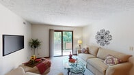 Located at 1514 Diamond Ct in Fort Wright, Kentucky, this single-floor residence offers a well-organized and comfortable layout across several distinct living spaces. The living room serves as the heart of the home, featuring plush carpeting, a textured ceiling, and a large sliding glass door that opens onto a private balcony with lush tree views, filling the space with natural light. Adjacent to the living room is a dedicated dining area, appointed with a classic chandelier, decorative wallpaper above wainscoting, and carpeted flooring — an inviting setting for meals and gatherings. The galley-style kitchen is efficiently designed with rich wood cabinetry, light countertops, a double basin sink, and tile flooring, providing ample storage and functionality. The residence includes two bedrooms, both carpeted and well-lit by windows with vertical blinds. The primary bedroom offers generous space, while the second bedroom provides a cozy, practical retreat. The full bathroom features a combination tub and shower with built-in shelving, complemented by neutral tiling. Throughout the home, a consistent color palette of warm neutrals and natural wood tones creates a cohesive and comfortable living environment.