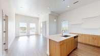 Located in Lakewood, Colorado, this well-appointed 2-bedroom, 2-bathroom residence offers a thoughtfully designed single-floor layout with modern finishes throughout. The open-concept living and kitchen area is bright and airy, benefiting from large windows that flood the space with natural light and provide outdoor views of the surrounding neighborhood. Soaring ceilings enhance the sense of openness in the main living area.

The contemporary kitchen is a standout feature, showcasing a central island with a white quartz countertop and undermount sink, warm wood-toned lower cabinetry paired with crisp white upper cabinets, a subway tile backsplash, and a full suite of stainless steel appliances including a refrigerator, range, microwave, and dishwasher. Stylish pendant lighting accents the island.

Both bedrooms are comfortably sized, carpeted for warmth, and receive generous natural light through large windows. The primary bedroom includes a walk-in closet with wire shelving. Each bathroom features a tub-shower combination with white subway tile surround, wood-toned vanity cabinetry, quartz countertops, and light tile flooring. A dedicated in-unit laundry nook with a washer/dryer provides added convenience. Wood-look flooring runs throughout the main living areas, completing the home's clean, modern aesthetic.