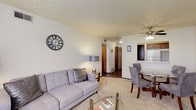 This single-floor residence at 4979 Kingshill Dr in Columbus, Ohio offers a practical and comfortable layout across several well-defined living spaces. The living room is carpeted and features a textured ceiling, a ceiling fan with integrated lighting, and a large window dressed with grommet-panel curtains that allow natural light to filter in. The open layout connects the living area to a dedicated dining space, creating a cohesive flow ideal for everyday living and entertaining. The kitchen is equipped with warm wood-toned cabinetry, light countertops, a stainless steel sink, a dishwasher, and white appliances including a refrigerator and stove. A pass-through window connects the kitchen to the dining area, enhancing the sense of openness. The bedroom is a quiet, carpeted retreat with a window providing natural light and ample space for furnishings. The bathroom features a white vanity with under-cabinet storage, a large mirror, and a tub-shower combination. Hardwood-style flooring is present in the kitchen and bathroom, complementing the neutral color palette carried throughout the unit. Overall, the space presents a clean, functional design suited for comfortable everyday living.