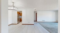 This single-floor home offers a practical and comfortable layout across three bedrooms and three bathrooms. The open living and dining area features light wood-style flooring, warm wood baseboards, and a textured ceiling. A modern geometric chandelier anchors the dining space, while two charming pass-through windows connect to the hallway, adding an architectural detail that enhances the flow between rooms. The living room is carpeted and benefits from a sliding glass door that opens to a balcony, bringing in natural light and outdoor views.

The kitchen is equipped with warm-toned oak cabinetry, granite countertops, a stainless steel refrigerator, and a double sink, offering a functional workspace. Each of the three bedrooms features neutral carpet, white walls, and a window fitted with blinds that allows natural light to filter in. The primary bedroom includes a walk-in closet with built-in shelving. The bathrooms are finished cleanly with white tub-shower combinations and tile flooring. Throughout the home, consistent wood baseboards and a neutral color palette create a cohesive and inviting atmosphere.