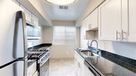 This single-floor residence offers a well-organized layout with a thoughtful mix of updated finishes and functional living spaces throughout. The living area is generously proportioned, featuring neutral-toned carpet, soft wall colors, and French doors that invite abundant natural light while providing views of the surrounding exterior. A dedicated utility area conveniently houses a stacked washer and dryer unit, accessible directly from the main living space.

The galley-style kitchen is efficiently designed with white cabinetry, dark granite countertops, stainless steel gas range, and an undermount sink with a modern brushed nickel faucet. Light marble-look tile flooring and a window overlooking greenery contribute to a bright, clean atmosphere.

The bedrooms are carpeted and well-lit by windows, with at least one room featuring a sliding-door closet offering organized shelving and hanging space. The bathrooms are notably updated, with one showcasing large-format marble-style wall tile surrounding a soaking tub with brushed gold fixtures, and another featuring a white vanity with integrated sink, marble-tile flooring, and a mirrored medicine cabinet. The overall aesthetic is clean, neutral, and move-in ready.