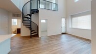 Located at 4868 Cypress St in Montclair, CA, this contemporary residence showcases an open, airy design highlighted by dramatically high ceilings in the main living area. A standout architectural feature is the sleek black spiral staircase, which adds a bold visual element while connecting to the upper loft-style mezzanine level complete with a ceiling fan. The open-concept living and kitchen area is finished with durable wood-tone flooring that flows seamlessly throughout. The kitchen is well-equipped with rich dark wood cabinetry, a classic white subway tile backsplash, quartz countertops, a spacious kitchen island with an undermount sink, and stainless steel appliances including a gas range, microwave, and refrigerator. Natural light fills the space through multiple windows fitted with blinds. Bedrooms offer comfortable carpet flooring, elevated windows for added privacy, and generous closet space — including a mirrored sliding-door closet and a dedicated walk-in closet with dual hanging rods. The bathrooms are clean and modern, featuring dark wood vanities with white quartz counters, tub-shower combinations with tiled surrounds, and wood-look flooring. The overall aesthetic is fresh, minimal, and move-in ready.
