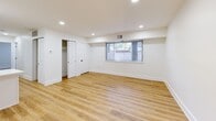 This thoughtfully renovated single-floor unit offers a clean, modern aesthetic throughout, highlighted by light-toned hardwood-style flooring and crisp white walls that create a bright and welcoming atmosphere. The open-concept living area flows seamlessly into the kitchen, which serves as a standout feature of the space. The kitchen is outfitted with white shaker-style cabinetry accented by matte black hardware, white quartz countertops, a full suite of stainless steel appliances including a gas range, microwave, dishwasher, and refrigerator, and a striking blue subway tile backsplash that adds a bold design element. A peninsula provides additional counter space and separation between the kitchen and living areas. Recessed lighting throughout the main living space enhances visibility and adds to the contemporary feel. The bedrooms are well-proportioned, each featuring wood-style flooring, white walls, and windows that allow natural light to filter in. The primary bedroom includes access to a generous walk-in closet with built-in shelving and hanging rods. The bathroom is finished with the same blue subway tile carried from the kitchen, wrapping the full tub-shower surround for a cohesive design, complemented by matte black fixtures and clean white tilework on the floor.