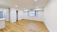 This thoughtfully renovated single-floor unit offers a clean, modern aesthetic throughout, highlighted by light-toned hardwood-style flooring and crisp white walls that create a bright and welcoming atmosphere. The open-concept living area flows seamlessly into the kitchen, which serves as a standout feature of the space. The kitchen is outfitted with white shaker-style cabinetry accented by matte black hardware, white quartz countertops, a full suite of stainless steel appliances including a gas range, microwave, dishwasher, and refrigerator, and a striking blue subway tile backsplash that adds a bold design element. A peninsula provides additional counter space and separation between the kitchen and living areas. Recessed lighting throughout the main living space enhances visibility and adds to the contemporary feel. The bedrooms are well-proportioned, each featuring wood-style flooring, white walls, and windows that allow natural light to filter in. The primary bedroom includes access to a generous walk-in closet with built-in shelving and hanging rods. The bathroom is finished with the same blue subway tile carried from the kitchen, wrapping the full tub-shower surround for a cohesive design, complemented by matte black fixtures and clean white tilework on the floor.