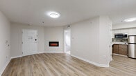 Located at 450 Technology Pkwy NW in Norcross, Georgia, this single-floor unit offers a clean, contemporary design with a cohesive neutral color palette throughout. Light wood-style flooring flows seamlessly across the main living areas, complementing the crisp white trim and soft beige walls to create a bright, welcoming atmosphere.

The living area serves as the focal point of the unit, anchored by a sleek wall-mounted electric fireplace that adds warmth and a modern touch. The open layout provides generous space for flexible furniture arrangements, with ceiling-mounted lighting ensuring a well-lit environment.

The kitchen is thoughtfully appointed with two-tone cabinetry — warm wood lower cabinets paired with white upper cabinets — along with white countertops, a mosaic tile backsplash, and stainless steel appliances including a dishwasher, microwave, and cooktop. The bedroom features a window fitted with blinds, allowing for natural light and outdoor views, while the bathroom is finished with large-format tile flooring, a combined tub and shower, and a wood-accented vanity with a clean white countertop. Throughout the unit, the consistent use of light tones and modern finishes creates a calm, functional living environment.