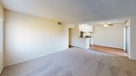 Located at 400 N Chapel Ave in Alhambra, California, this single-floor residence offers a thoughtfully designed layout with a blend of comfort and functionality. The open-concept living area is carpeted and bathed in natural light, flowing seamlessly into a semi-open kitchen defined by a peninsula counter. The kitchen features white cabinetry, stainless steel appliances including a range and refrigerator, and overhead lighting that brightens the workspace. A ceiling fan overhead and sliding door access add to the practicality of the adjoining dining area, which features warm hardwood-style flooring. The bedroom is generously sized with plush carpet, a ceiling fan with light fixture, and a sliding glass door that invites natural light and outdoor views. A mirrored sliding-door closet provides ample storage. The bathroom is clean and well-appointed, showcasing a granite-style countertop vanity, a large mirror, and a bathtub. Additional closet storage with built-in shelving and hanging rods is also present. Outside, residents enjoy access to a sparkling community pool surrounded by lounge seating, mature trees, and well-maintained landscaping, all set against the backdrop of the multi-story building exterior in a serene Alhambra setting.