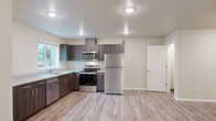 Located at 1041 Schurman Dr S in Salem, Oregon, this single-story, 3-bedroom, 2-bathroom home offers a functional and well-appointed layout. The open kitchen and living area serves as the heart of the home, featuring dark wood cabinetry, light countertops, and a full suite of stainless steel appliances including a refrigerator, electric range, microwave, and dishwasher. Recessed lighting and a large window bring natural light into the space, which is finished with durable light-toned luxury vinyl plank flooring throughout. The three bedrooms offer a mix of LVP and plush carpeted flooring, with the primary bedroom providing a comfortable, generously sized retreat. Closets with built-in shelving and hanging rods offer practical storage. The two bathrooms include one with a full soaking tub and shower combination and another with a walk-in shower, both finished in clean white fixtures. A dedicated laundry room houses a full-size washer and dryer. A wall-mounted mini-split unit provides heating and cooling. The hallway connects all rooms efficiently, and neutral beige tones throughout create a clean, move-in ready environment.