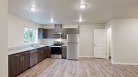 Located at 1041 Schurman Dr S in Salem, Oregon, this single-story, 3-bedroom, 2-bathroom home offers a functional and well-appointed layout. The open kitchen and living area serves as the heart of the home, featuring dark wood cabinetry, light countertops, and a full suite of stainless steel appliances including a refrigerator, electric range, microwave, and dishwasher. Recessed lighting and a large window bring natural light into the space, which is finished with durable light-toned luxury vinyl plank flooring throughout. The three bedrooms offer a mix of LVP and plush carpeted flooring, with the primary bedroom providing a comfortable, generously sized retreat. Closets with built-in shelving and hanging rods offer practical storage. The two bathrooms include one with a full soaking tub and shower combination and another with a walk-in shower, both finished in clean white fixtures. A dedicated laundry room houses a full-size washer and dryer. A wall-mounted mini-split unit provides heating and cooling. The hallway connects all rooms efficiently, and neutral beige tones throughout create a clean, move-in ready environment.