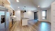 Located at 1350 40th St in Denver's vibrant Cole neighborhood, this thoughtfully designed one-bedroom, one-bathroom unit offers a contemporary living experience with high-quality finishes throughout. The open-concept living and kitchen area is anchored by warm wood-look luxury vinyl plank flooring, recessed lighting, and a central kitchen island with a dark countertop and striking black pendant lights overhead. The kitchen is well-appointed with light wood cabinetry, a bold blue subway tile backsplash, stainless steel appliances including a gas range, built-in microwave, refrigerator, and dishwasher, as well as a gold-toned pull-down faucet. The living area benefits from abundant natural light through floor-to-ceiling sliding glass doors that open to an outdoor area, complemented by an additional side window. The bedroom features plush carpeting, a ceiling fan, and a window with outdoor views. A spacious walk-in closet with built-in shelving and hanging rods provides ample storage. The bathroom is elegantly finished with a wood-toned vanity, dark countertop, black hardware accents, and a glass-enclosed walk-in shower with dark vertical tile, completing this modern and cohesive living space.