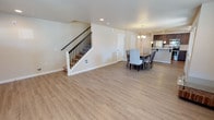 Located at 505 Greenwood Dr in Olympia, Washington, this well-appointed two-story home offers a thoughtfully designed layout across two levels. The main floor features an open-concept living and dining area with light-toned luxury vinyl plank flooring that extends throughout, creating a clean and cohesive aesthetic. A staircase with a classic white balustrade and dark metal balusters anchors the main living space, adding a refined architectural detail.

The dining area is positioned adjacent to the kitchen and is illuminated by a stylish chandelier, making it an ideal space for entertaining. The kitchen is a standout feature, equipped with rich dark wood cabinetry, light quartz countertops, a classic white subway tile backsplash, and a full suite of stainless steel appliances including a refrigerator, range, and microwave. A peninsula provides additional counter space and a casual dining option.

Upstairs, multiple bedrooms offer plush carpeting, warm neutral wall tones, and windows that invite natural light and views of the surrounding greenery. The bedrooms are generously sized, providing flexible use as sleeping quarters, a home office, or additional living space. The upper hallway connects the rooms in a practical and efficient layout. Overall, this home presents a modern, move-in-ready environment with quality finishes throughout.