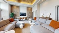 Located at 144 Langdon Street in Madison, Wisconsin, this sophisticated 940-square-foot single-floor lounge space offers an exceptional blend of modern design and natural beauty. The open-plan layout is anchored by dramatic floor-to-ceiling windows that line an entire wall, flooding the interior with natural light and framing breathtaking panoramic views of Lake Mendota and the surrounding cityscape.

The space features soaring ceilings with a striking tray detail finished in warm wood paneling, illuminated by recessed lighting that adds a golden ambiance. A wall-mounted linear fireplace set against a full-height reclaimed wood accent wall serves as a bold focal point, complemented by floating wood shelves for display. The polished stone tile flooring extends seamlessly throughout, adding texture and a refined, upscale feel.

The lounge area is furnished with generous sectional sofas in neutral tones accented with burnt orange pillows, sculptural woven lounge chairs, and organic-shaped side tables. A separate dining area features a rustic wood table surrounded by woven rattan chairs beneath an artistic pendant fixture. An adjacent balcony provides direct outdoor access with unobstructed lake views. This space is ideal for social gatherings, offering a seamless connection between luxury interiors and stunning natural surroundings.