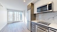 Located in the heart of downtown Montréal, this 1-bedroom, 1-bathroom penthouse unit at 400 Boul René-Lévesque O offers a thoughtfully designed, modern living space with a clean, contemporary aesthetic. Light hardwood flooring runs throughout, complementing the bright white walls and abundant natural light that flows in from large floor-to-ceiling windows offering sweeping city skyline views.

The open-concept kitchen is outfitted with two-tone cabinetry in white and matte grey, stainless steel appliances including a built-in oven, microwave, dishwasher, and full-size refrigerator, and a striking marble-style backsplash that adds a touch of elegance. The adjacent living area benefits directly from the expansive windows, creating a seamless, airy atmosphere.

The bedroom is a well-proportioned, sun-filled retreat with its own large window framing Montreal's urban landscape, a dedicated closet, and the same warm hardwood flooring found throughout the unit.

The bathroom is a refined space featuring full marble-effect wall and floor tiling, a frameless glass sliding shower enclosure, a modern floating vanity, and recessed lighting, lending a spa-like quality to the room.

Compact yet efficient, this penthouse unit is ideally suited for urban living in one of Montréal's most vibrant central locations.
