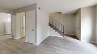 This two-story, 2-bedroom, 2-bathroom home in Decatur, Georgia offers a practical and straightforward layout spread across two floors. The main level features a bright, open living area with light wood-style flooring and neutral-toned walls, creating a clean and airy atmosphere. A carpeted staircase with sleek black metal railings connects the two floors. The kitchen is equipped with white cabinetry, a white electric range, a built-in exhaust hood, and gray countertops, with in-unit washer hookups conveniently located nearby. Both bathrooms are finished with light flooring and neutral walls; one includes a full tub-shower combination with white tile surround and a gray countertop vanity. Upstairs, both bedrooms are generously sized with soft wall-to-wall carpeting, ceiling fans, and natural light from windows. The spacious primary bedroom includes access to a dedicated closet. The secondary bedroom also features a ceiling fan and a closet. Each room is finished with crisp white trim and neutral paint throughout, giving the home a clean, move-in-ready feel. A hallway connects the upper-level rooms, and additional closet storage is available on both floors.
