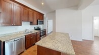 Located on the first floor at 48 High St in Bristol, Connecticut, this three-bedroom, one-bathroom unit offers a well-designed single-level layout with modern finishes throughout. Wood-look tile flooring runs seamlessly across the living areas and bedrooms, lending a warm, cohesive aesthetic to the space.

The kitchen is a standout feature, appointed with rich dark-wood cabinetry, granite countertops, a central island for added prep and dining space, and a full suite of stainless steel appliances including a refrigerator, range, microwave, and dishwasher. The open feel of the kitchen flows naturally into the surrounding living area.

Each of the three bedrooms is bright and well-proportioned, with natural light provided by double-hung windows fitted with blinds. The bedrooms are equipped with individual wall-mounted mini-split units for personalized climate control, and select rooms include closet storage.

The bathroom is spacious and functional, featuring a clean white vanity with a mirror, and a stacked washer and dryer unit conveniently integrated into the same room, eliminating the need for a separate laundry area. Crisp white walls and wood-look vinyl flooring complete the clean, modern look. A hallway connects the rooms efficiently throughout the single-floor layout.