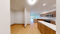 Located at 110 Roy St in Seattle's Queen Anne neighborhood, this thoughtfully designed 1-bedroom, 1-bathroom residence offers a clean, modern aesthetic throughout. Light bamboo-style hardwood flooring runs continuously across the entire space, lending warmth and visual continuity to every room.

The open-concept kitchen and living area serves as the heart of the home. The kitchen is outfitted with rich walnut-toned cabinetry, white quartz countertops, a subway tile backsplash, and a full suite of stainless steel appliances including a refrigerator, range, and built-in microwave. A central island with a waterfall countertop and an undermount sink doubles as a dining and prep area, accented by stylish pendant lighting overhead.

The living and dining areas flow seamlessly from the kitchen, offering a bright, open feel with recessed lighting and large windows that invite natural light and frame views of the Seattle cityscape and surrounding greenery.

The bedroom is a calm, well-proportioned retreat featuring expansive windows with urban views, clean white walls, and direct access to the bathroom. The bathroom mirrors the home's modern design with a wood-front vanity, white countertop, and a combined tub and shower. A dedicated closet and in-unit laundry complete this well-appointed residence.