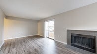 Located at 3304 Golden Rd in Tyler, TX, this efficiently designed single-floor unit offers a thoughtful layout that maximizes every square foot. The living room serves as the focal point of the space, featuring a tile-surround fireplace with a classic white mantel and a sliding glass door that invites natural light and provides outdoor access. Neutral-toned walls and durable wood-look flooring in a gray-washed finish extend throughout the unit, creating a cohesive and modern aesthetic. A closet with sliding white panel doors adds convenient storage directly within the living area. The kitchen is well-appointed with white shaker-style cabinetry, a white subway tile backsplash, light countertops, and a full suite of stainless steel appliances including a refrigerator, dishwasher, microwave, and range. Recessed lighting illuminates the kitchen workspace. The unit includes two bathrooms, one of which features a clean, fully tiled soaking tub and shower combination with built-in corner shelving. An additional utility or storage room with a built-in shelf provides extra functional space. The textured ceilings and clean white trim throughout contribute to a fresh, move-in-ready feel.