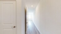 This two-story home presents a clean, contemporary design defined by a neutral color palette, light wood-style flooring, and an abundance of natural light. The main level offers an open-concept layout where the kitchen flows seamlessly into the living area. The kitchen is well-appointed with white shaker-style cabinetry, granite-look countertops, and a full suite of stainless steel appliances, including a side-by-side refrigerator with ice and water dispenser, an electric range, over-the-range microwave, and dishwasher. Multiple windows along the main living area allow natural light to fill the space, enhancing the airy, open feel. A half bathroom on the main level features wood-look tile flooring, a pedestal sink, and chrome fixtures. A long, well-lit hallway with recessed lighting and clean white walls connects the various areas of the home. Upstairs, carpeted bedrooms provide a comfortable retreat, with dual windows offering ample natural light. A full bathroom on the upper level includes a tub-shower combination, a single-sink vanity with white cabinetry, and wood-look tile flooring. Throughout both floors, crisp white trim and doors, recessed lighting, and a cohesive neutral palette contribute to a bright, move-in-ready atmosphere.