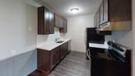 Located at 5277 W 82nd St in Bloomington, Minnesota, this single-floor unit offers a well-organized layout with updated finishes throughout. The kitchen is a standout feature, showcasing rich dark-stained cabinetry paired with crisp white quartz countertops and a classic subway tile backsplash. Stainless steel appliances, including a refrigerator and electric range, complete the space, which is finished with durable hardwood-style flooring for a modern, cohesive look.

The living area is open and airy, benefiting from a large bank of windows that invites generous natural light and provides views of the surrounding greenery. The same hardwood-style flooring carries through, lending visual continuity to the space. Ceiling fans are present in both the living and sleeping areas, contributing to comfortable year-round climate management.

The bedroom is a calm retreat, featuring plush carpeting, a ceiling fan, and a window with outdoor views. A closet with louvered doors provides practical storage. The bathroom is clean and functional, featuring a full soaking tub and shower combination with white subway tile surround and chrome fixtures. Textured ceilings are consistent throughout the unit, adding a subtle architectural detail to the overall interior.
