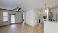 This single-story, one-bedroom, one-bathroom unit offers a thoughtfully designed layout with modern finishes throughout. Light-toned wood-look flooring extends across the entire space, creating a cohesive and easy-to-maintain foundation. The open living area is bright and airy, with natural light filtering through blinds-covered windows and a ceiling fan overhead providing year-round comfort. Crown molding adds a refined touch to the main living space.

The kitchen is well-equipped, featuring dark espresso cabinetry with sleek hardware, granite countertops, stainless steel appliances including a refrigerator and electric range, and a peninsula that opens toward the dining area. A modern chandelier anchors the dining space. Conveniently, a dedicated laundry area is accessible directly from the kitchen.

The bedroom is comfortably sized with its own ceiling fan, a window for natural light, and direct access to a walk-in closet. The bathroom includes a dark-cabineted vanity topped with granite, a large mirror, and quality fixtures. The neutral color palette and clean lines throughout lend the space a modern, move-in-ready ambiance.