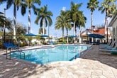 This 1,130-square-foot, single-floor condo at 1331 S Federal Hwy, Unit N-202, in Boynton Beach, FL features 3 bedrooms and 2 bathrooms thoughtfully arranged across one level. The open-concept living and dining area is finished with warm wood-look flooring, crisp white walls, and ceiling fans, creating a bright and airy atmosphere. Large windows and a glass-paneled front door allow abundant natural light throughout. The kitchen is a standout feature, boasting rich dark-wood cabinetry, quartz countertops, a decorative tile backsplash, and a full suite of stainless steel GE appliances including a refrigerator, range, and microwave. A kitchen island provides additional counter space and storage. The bedrooms are well-proportioned — the primary bedroom measures 160 square feet — each with wood-look flooring and ceiling fans. The bathrooms feature tile flooring, dark-wood vanities with quartz countertops, and glass-enclosed showers. A dedicated walk-in closet offers wire-shelf storage. The in-unit laundry room houses a full-size GE washer and dryer alongside a water heater. A hallway connects the living spaces seamlessly, completing this well-designed, functional home.