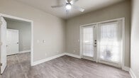 This efficiently designed 1-bedroom, 1-bathroom unit offers a thoughtful layout across a single floor, making excellent use of its compact footprint. Light gray hardwood-style flooring runs throughout the entire space, creating a cohesive and modern aesthetic.

The open living area features neutral taupe walls, crisp white baseboards, and a ceiling fan with integrated lighting. A glass-paned door with slatted blinds allows natural light to filter in while providing direct access to the outdoors.

The galley-style kitchen is a standout feature, showcasing soft blue-gray shaker cabinetry paired with white quartz countertops and a marble-look tile backsplash. A full suite of stainless steel appliances—including a refrigerator, range, microwave, and dishwasher—provides a complete and functional cooking space. A skylight overhead adds an airy brightness to the kitchen.

The bedroom is a comfortable, well-lit retreat with two windows that invite natural light and a ceiling fan above. A dedicated closet provides practical storage.

The bathroom continues the blue-gray cabinetry theme, featuring a wide vanity with white quartz countertop, a large framed mirror, and a tub-shower combination with elegant marble-look surround tile. The overall design is clean, modern, and cohesive throughout.