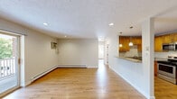 Located at 15 Dolores Ave in Waltham, MA, this two-bedroom, one-bathroom residence offers a well-organized single-floor layout with consistent hardwood flooring throughout. The open living area is bright and spacious, featuring recessed lighting, a textured ceiling, baseboard heating, and a wall-mounted air conditioning unit. A peninsula with granite countertops connects the living space to the kitchen, which is outfitted with warm wood cabinetry, granite countertops, a stainless steel range, microwave, and refrigerator, all illuminated by pendant lighting overhead. The primary bedroom is a comfortable size with a built-in closet and a wall A/C unit, while the second bedroom benefits from natural light and easy access to the main living area. A sliding glass door in one of the rooms opens to an outdoor view of the brick exterior. The full bathroom is finished with marble-style tile surrounds, a tub-shower combination, a wood vanity with a granite countertop, and tile flooring. Both bedrooms feature hardwood floors and ample natural light. The overall aesthetic is clean and functional, with neutral tones and practical finishes throughout this Waltham residence.