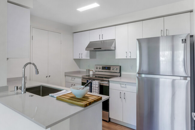 Renovated III kitchen with white cabinetry, grey quartz countertops, stainless steel appliances, and hard surface flooring - Archstone Redmond Lakeview