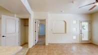 This single-story, one-bedroom, one-bathroom home offers a thoughtfully arranged floor plan that maximizes every square foot. The living room serves as a welcoming entry point, featuring warm beige tile flooring, a ceiling fan with light fixture, and large windows alongside a front door with decorative glass panels that flood the space with natural light and views of the surrounding greenery. A charming arched wall niche adds a distinctive architectural touch, providing a decorative focal point throughout the common areas.

The kitchen is outfitted with warm wood-toned cabinetry, stone-look countertops, and recessed lighting, offering practical storage and workspace. An additional arched niche accent in the kitchen area maintains the home's consistent design language.

The bedroom is a comfortable retreat with wood-look plank flooring, a ceiling fan, and a window that invites natural light. It provides direct access to a spacious walk-in closet equipped with multiple hanging rods and shelving on wood-look flooring, along with a small window for ventilation.

The bathroom features tile flooring, a wood-toned vanity with a stone-look countertop, a large mirror, and a tiled shower enclosure. A dedicated laundry area with built-in shelving completes this well-appointed home.
